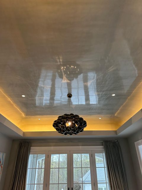 A ceiling painted with high gloss paint and a chandelier