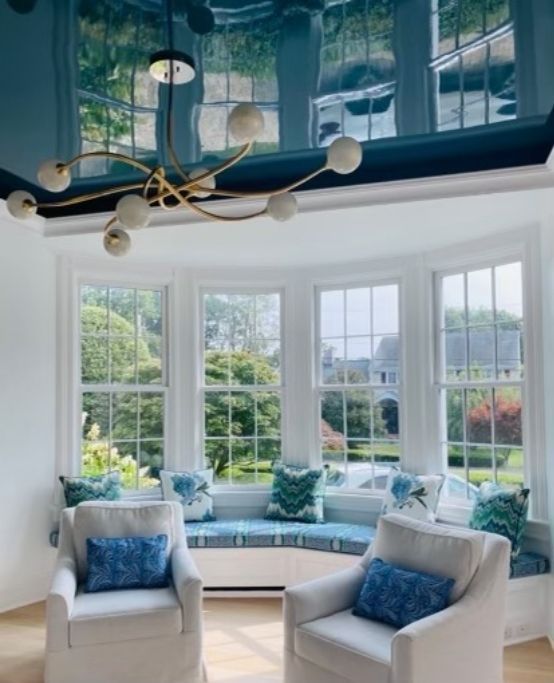 Teal high gloss ceiling accenting a room with white walls and large windows
